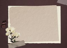 an empty piece of paper with some flowers in front of it on a brown background