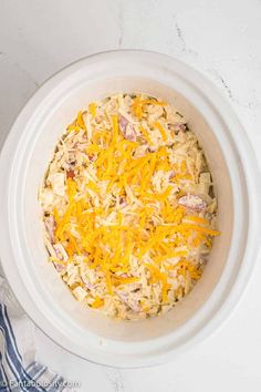 a white bowl filled with cheese and other food items on top of a marble counter