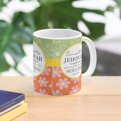 a coffee mug sitting on top of a wooden table next to a book and plant