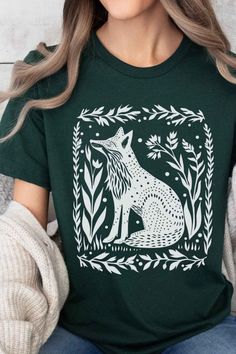 Embrace the granola girl aesthetic with this charming fox shirt! Featuring a beautiful linocut design inspired by folk art, this shirt is perfect for nature lovers and free spirits. Add a touch of woodland whimsy to your wardrobe with this delightful piece! 🍃🦊 #GranolaGirl #GranolaGirlAesthetic #FoxHoodie #LinocutHoodie #FolkArt Green Crew Neck Shirt With Funny Print, Printed Graphic Tee With Crew Neck, Green Short Sleeve T-shirt With Custom Print, Printed Graphic Tee Shirt With Crew Neck, Green Funny Print Graphic Tee Shirt, Green Custom Print Short Sleeve T-shirt, Green Short Sleeve Top With Funny Print, Linocut Shirt, Granola Girl Aesthetic Outfits