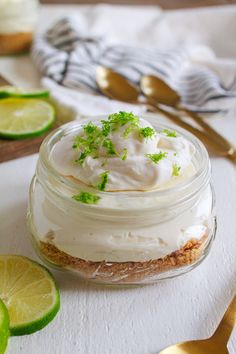 a jar filled with whipped cream and limes on top of a white table cloth