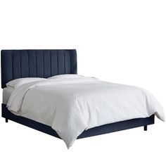 a bed with white sheets and blue headboard