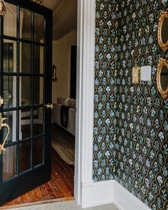 an open door leading to a living room with wallpaper and gold accents on the walls