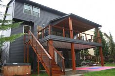 a house with a deck and hot tub in the yard next to stairs leading up to it