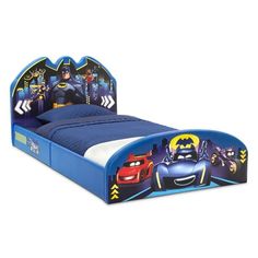 a blue bed with batman and cars on the headboard is in front of a white background