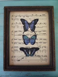 three blue butterflies sitting on top of sheet music with musical notes in front of them