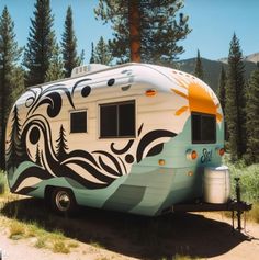 an rv parked on the side of a dirt road in front of some pine trees