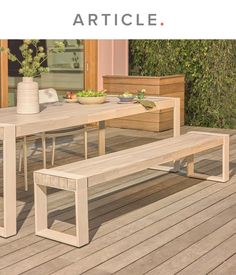 a table and bench on a wooden deck with plants in the background that reads article