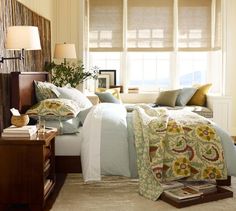 a bed sitting in a bedroom next to a window with lots of pillows on top of it