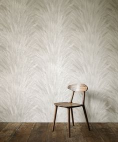 a chair sitting on top of a wooden floor next to a wall with a plant pattern