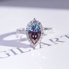 a ring with a blue and brown diamond in it sitting on top of a table