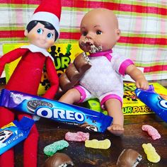 two elfs are eating candy while sitting on a table next to some candies