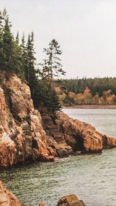 a man standing on top of a rock next to the ocean