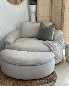 a living room with a round couch and mirror on the wall next to a plant