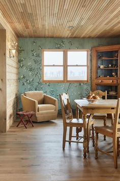 a dining room with wooden floors and green wallpaper on the walls, along with two chairs