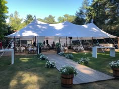 a large white tent set up in the middle of a field with tables and chairs