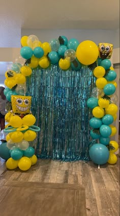 the balloon arch is decorated with yellow and teal balloons, blue streamers, and spongebob