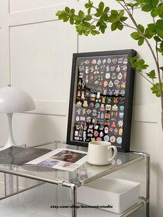 a glass table topped with a coffee cup next to a plant and a framed photo