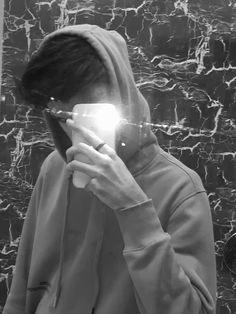 black and white photograph of a person in front of a mirror holding a cell phone