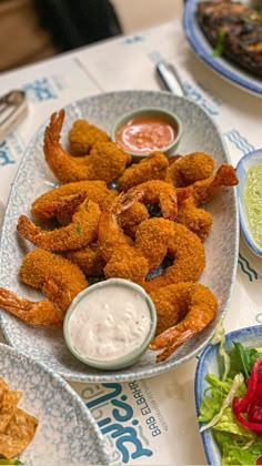 there are many different types of food on the table and one is fried shrimp with dipping sauce