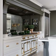 a large kitchen with white cabinets and gold trim on the stove top, along with an island