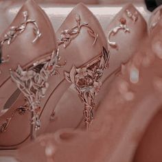 several pairs of pink shoes are lined up in a row on the floor and one is wearing an elaborately decorated shoe