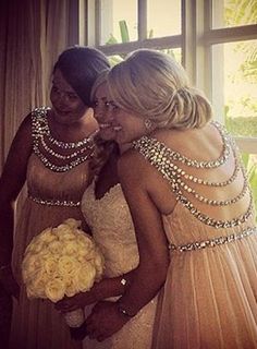 two beautiful women standing next to each other in front of a window holding bouquets