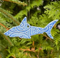 a blue ceramic fish ornament hanging from a tree