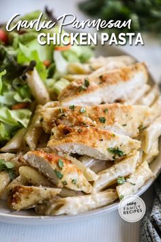 chicken pasta with parmesan cheese and herbs on the side in a white bowl