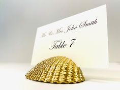 a gold ring sitting on top of a table next to a white card that says mr and mrs john smith