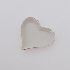 a white heart shaped dish sitting on top of a table