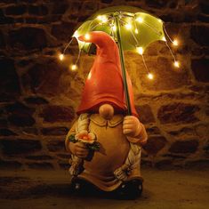 a garden gnome holding an umbrella with fairy lights on it