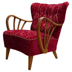 a red chair with wooden legs and arm rests against a white background, it appears to be in the style of art deco