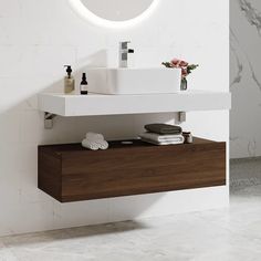 a white sink sitting under a round mirror next to a wall mounted faucet