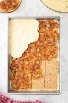 a pan filled with crackers and cheese on top of a counter next to other ingredients