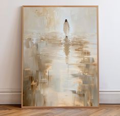 a painting on the wall with a person walking in the water behind it, and an empty wooden frame