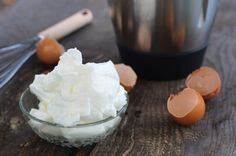 whipped cream in a glass bowl next to eggs