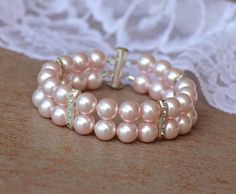 Our Pink Blush Pearl cuff has been made with soft pink Swarovski pearls in a classic two strand style embellished with crystal in silver bar accents for a sophisticated touch to your wedding day. This shade of pink is one the popular wedding color list for 2016/2017 bridal seasons. Perfect for the Bridemaids wearing pink. Closed with a silver slide clasp.Customize from our extensive pearl selectionMeasurements:Width - 7/8" (2 cm)Please choose a 'comfortable' wrist measurement and we will add a s Classic Adjustable Pink Bracelets, Adjustable Classic Pink Bracelets, Pink Pearl Bracelet For Wedding, Formal Pink Pearl Bracelet, Pink Pearl Bracelet With Round Beads For Formal Occasions, Elegant Pink Round Bead Bracelet, Elegant Pink Pearl Beaded Bracelets, Pink Beaded Pearl Bracelet For Wedding, Wedding Beaded Pink Pearl Bracelet