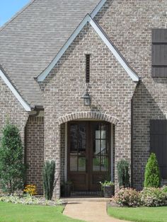 a brick house with black shutters on the front door