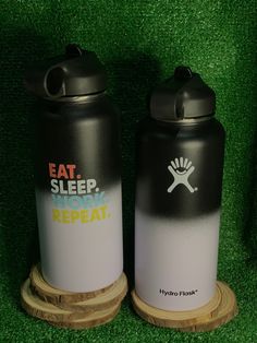 two black and white water bottles sitting next to each other on top of green grass