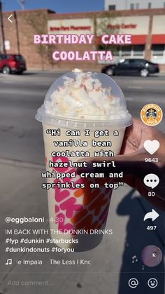 a person holding up a cup of ice cream in front of a street with cars