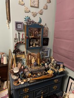 an old dresser is covered with pictures, figurines and other things on display