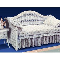 a white wicker daybed sitting on top of a blue rug next to a table