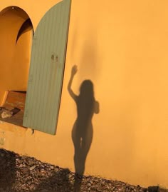 the shadow of a person standing in front of a building with an arched window and door