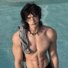 a shirtless young man standing in front of a pool with his hands on his hips