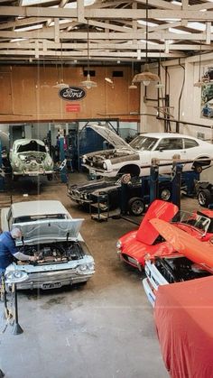 an auto shop with several cars in the garage and two men working on their hoods