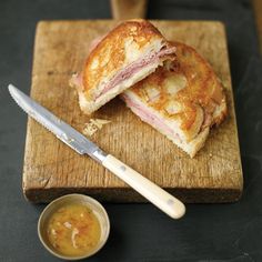 a sandwich cut in half sitting on top of a cutting board next to a knife