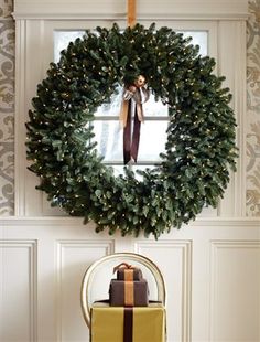 a christmas wreath hanging on the wall next to a chair with presents in front of it