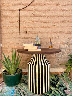 a black and white striped vase sitting on top of a table next to a potted plant