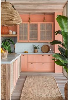 a pink kitchen with wicker cabinets and rugs on the floor in front of it